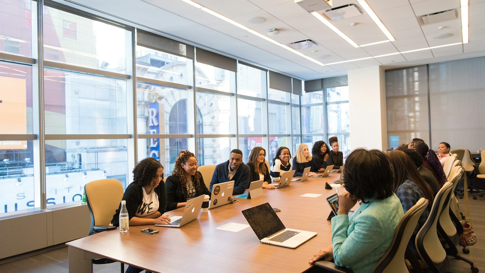 Pessoas em reunião de equipe ao redor de uma mesa com notebook
