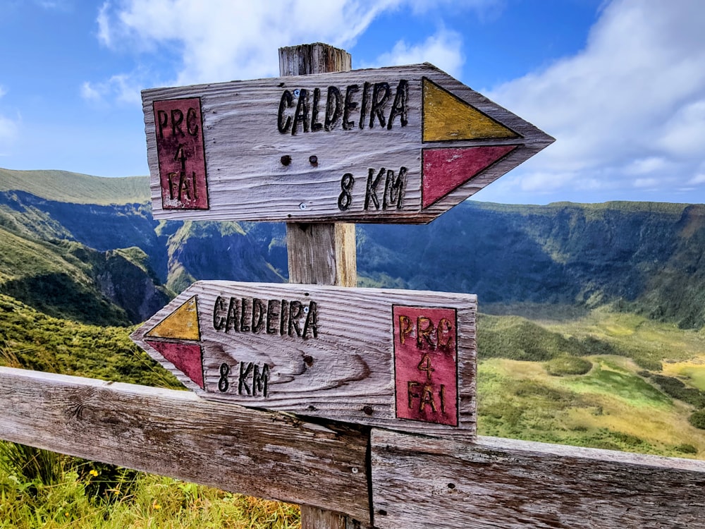 Duas placas de madeira apontando em direções opostas em uma trilha de montanha